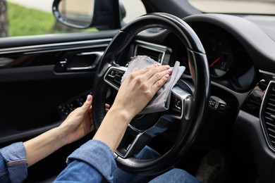 Photo of Woman wiping her modern car with rag, closeup