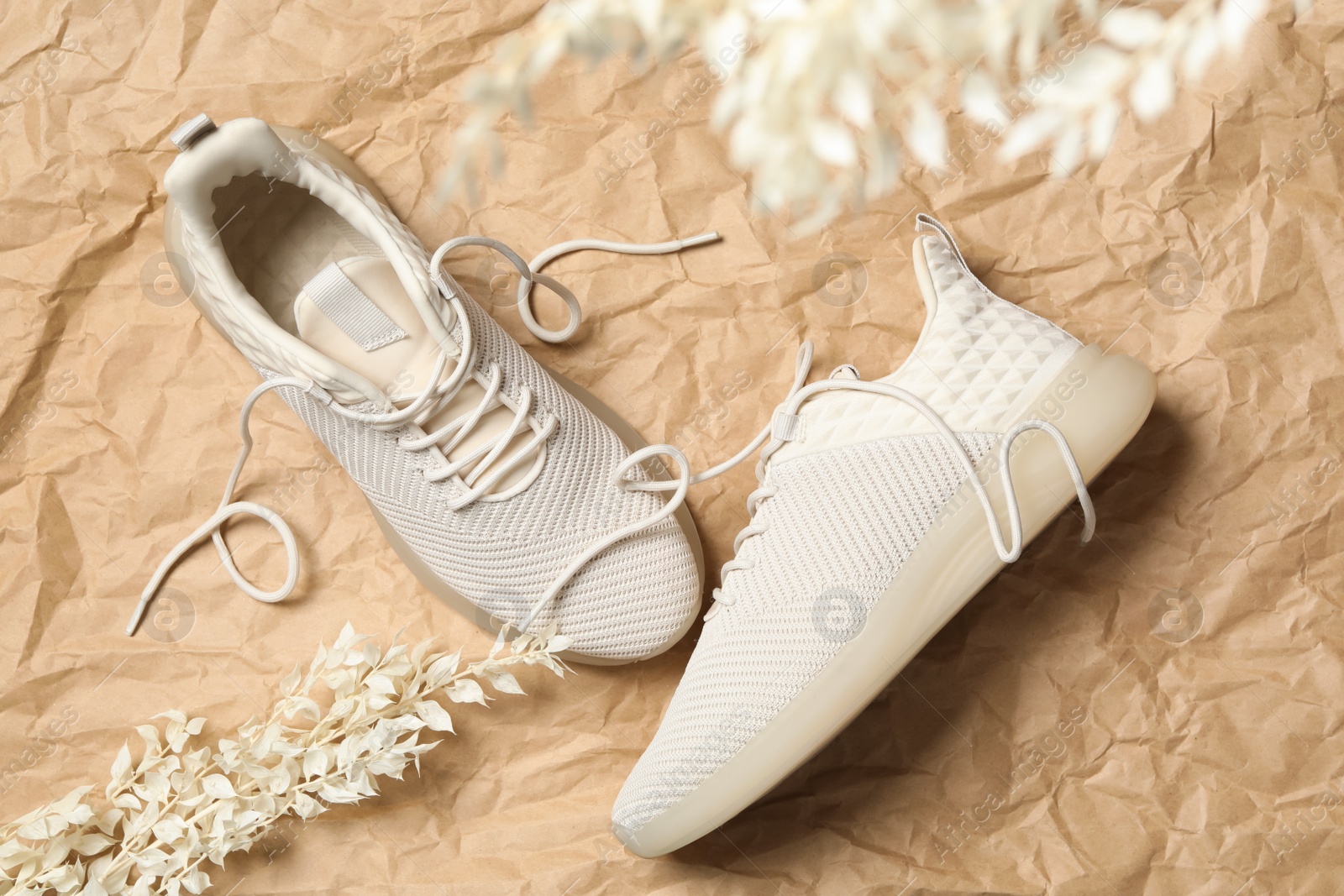 Photo of Pair of stylish shoes with laces on crumpled craft paper, flat lay