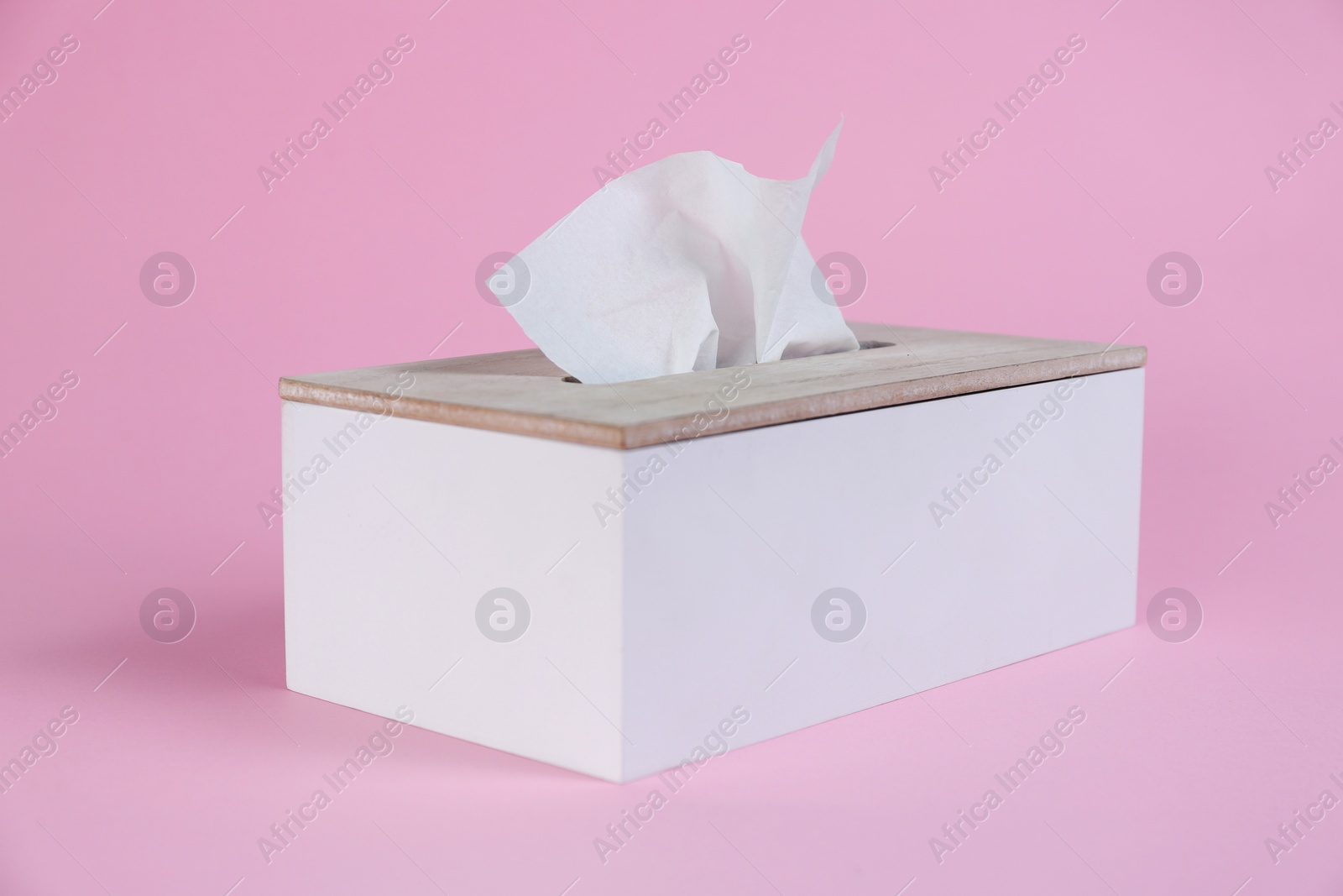 Photo of Holder with paper tissues on pink background