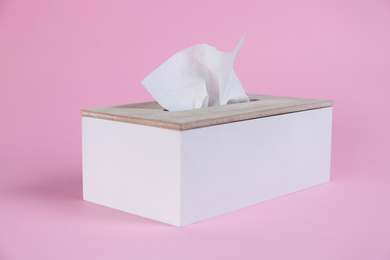 Photo of Holder with paper tissues on pink background