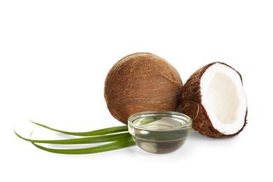 Ripe coconuts and bowl with natural organic oil on white background
