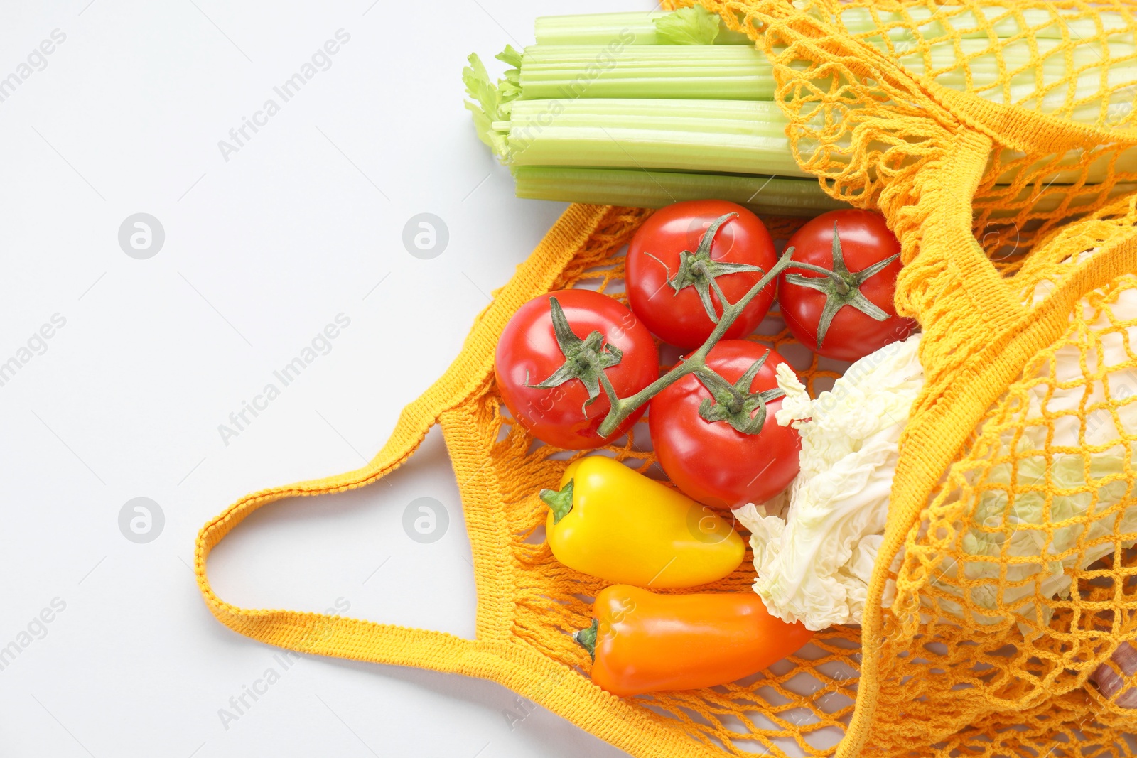 Photo of String bag with different vegetables on light grey background, top view