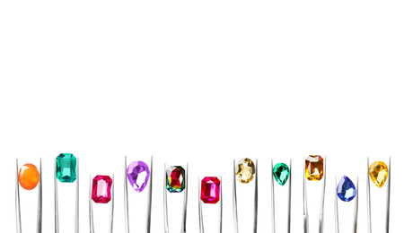 Set of tweezers with different shiny gemstones on white background. Banner design