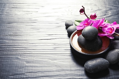 Photo of Composition with orchid flowers and spa stones on dark wooden background. Space for text