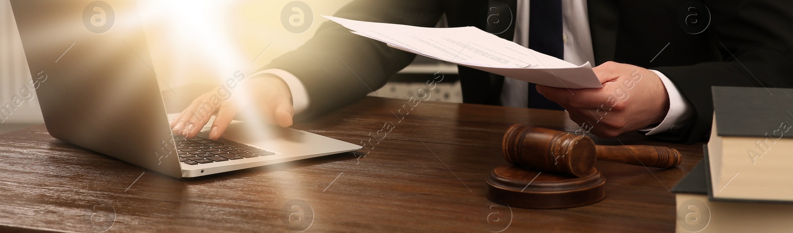 Image of Law and justice. Lawyer working with documents and laptop at wooden table, closeup. Banner design