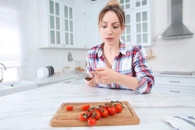 Photo of Woman cut finger with knife while cooking in kitchen