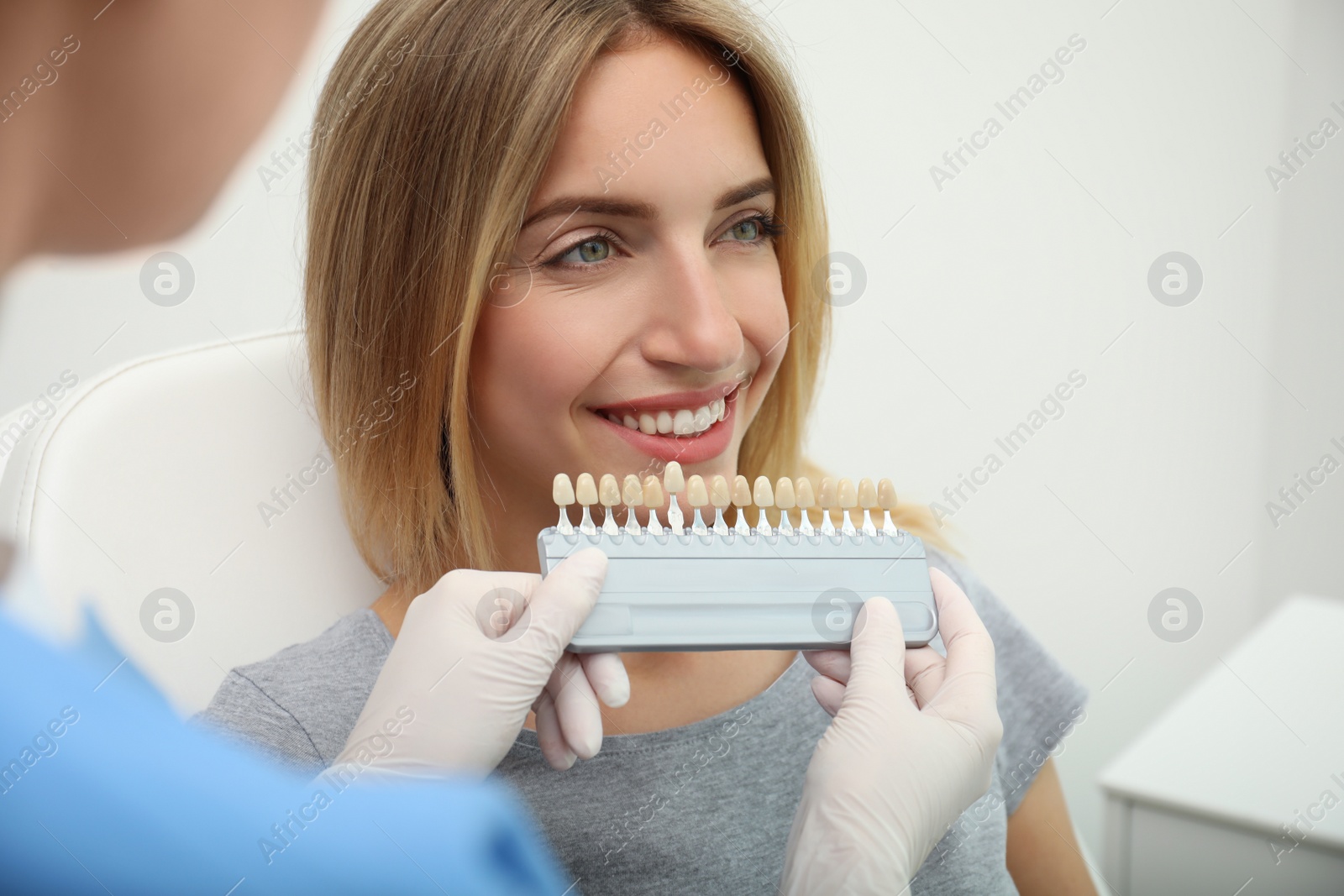 Photo of Doctor matching patient's teeth color with palette in clinic, closeup. Cosmetic dentistry