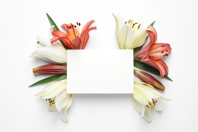 Photo of Blank card with fresh lily flowers on white background, top view. Space for text