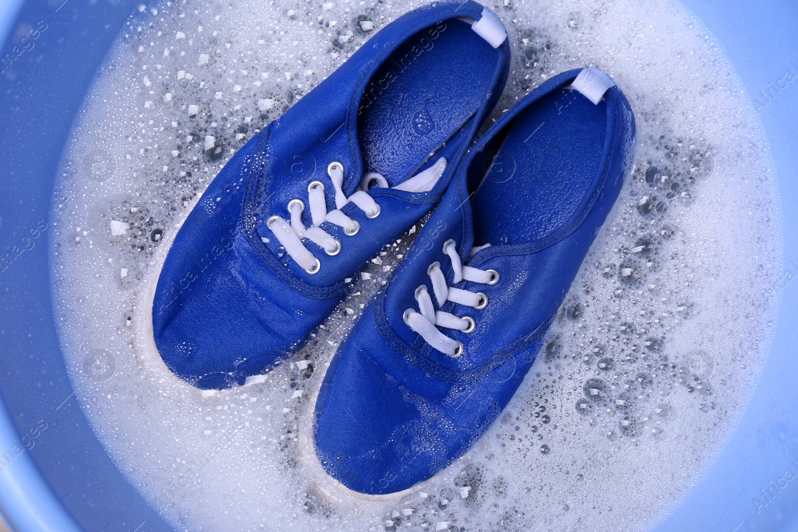 Photo of Washing sport shoes in plastic basin, top view