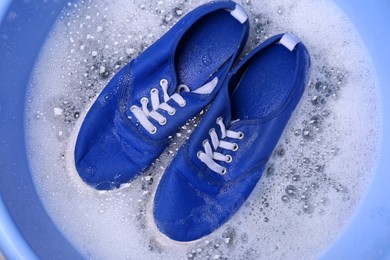 Photo of Washing sport shoes in plastic basin, top view