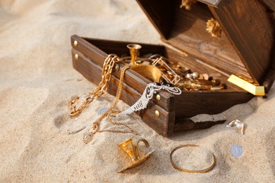 Open wooden chest with treasures on sand