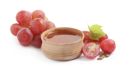 Organic red grapes, seeds and bowl of natural essential oil on white background