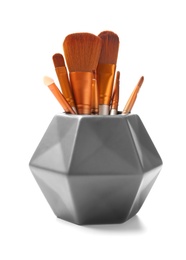 Holder with makeup brushes of professional artist on white background