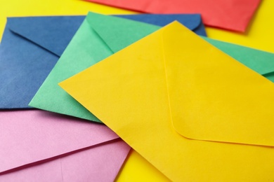 Photo of Colorful paper envelopes on yellow background, closeup
