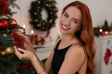 Photo of Happy young woman decorating Christmas tree at home