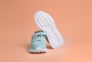 Photo of Pair of comfortable sports shoes on pale coral background. Space for text