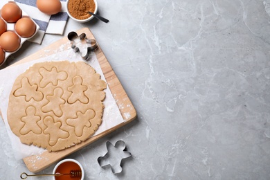 Photo of Making homemade Christmas cookies on grey marble table, flat lay with space for text. Gingerbread men