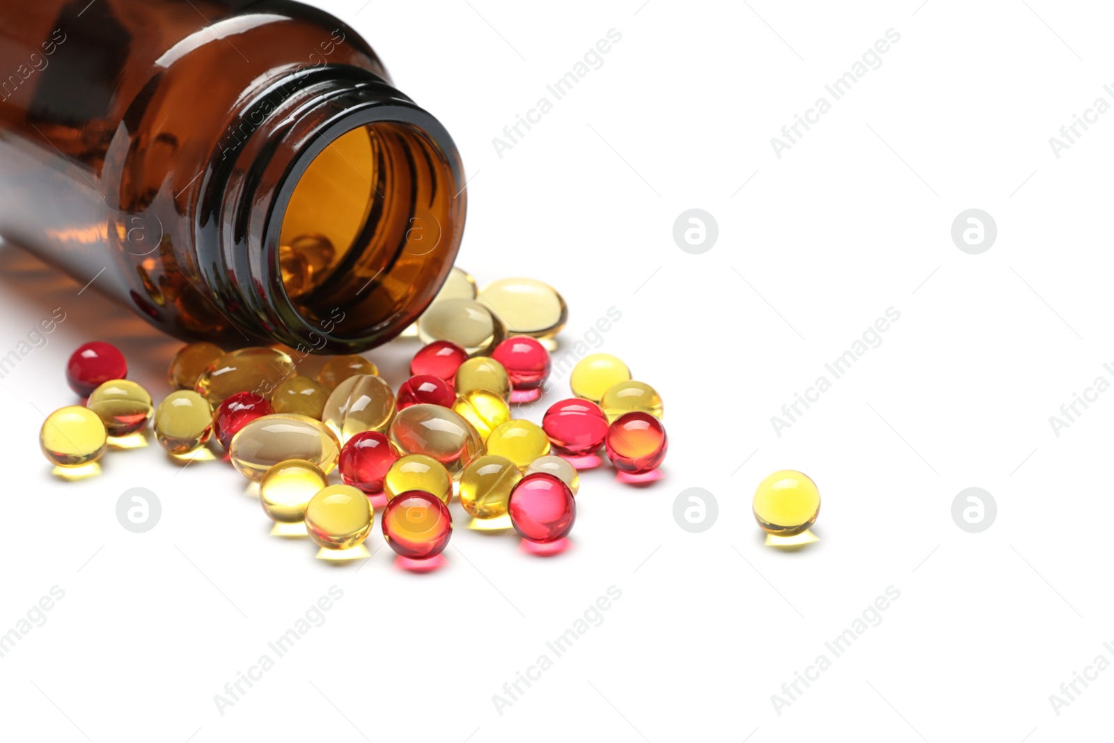 Photo of Bottle with different vitamin capsules on white background