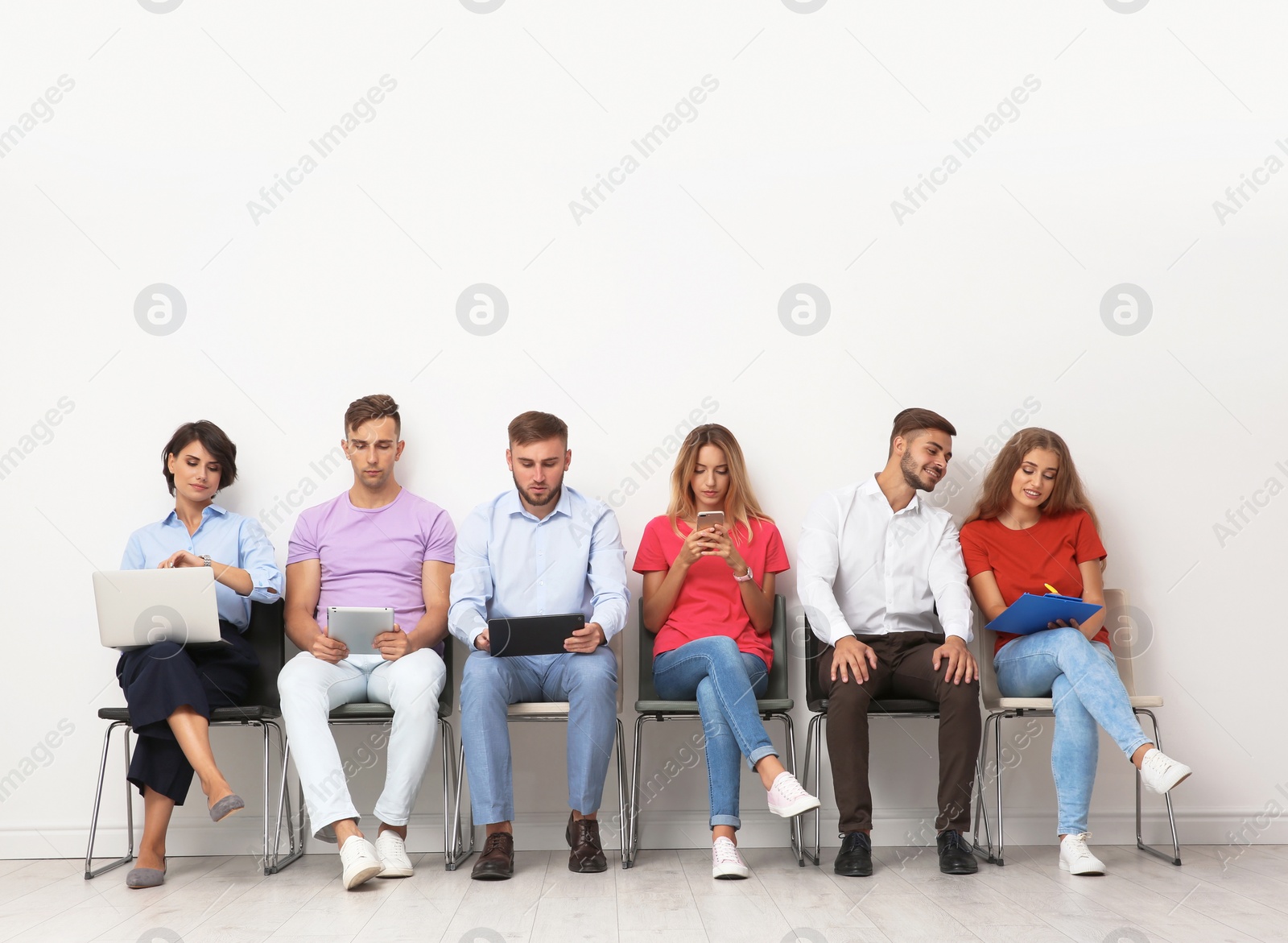 Photo of Group of young people waiting for job interview near light wall