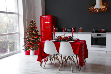 Stylish kitchen interior with festive table and decorated Christmas tree