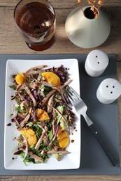 Photo of Delicious salad with beef tongue, orange, onion and fork served on wooden table, flat lay