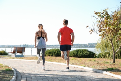 Sporty couple running outdoors on sunny morning