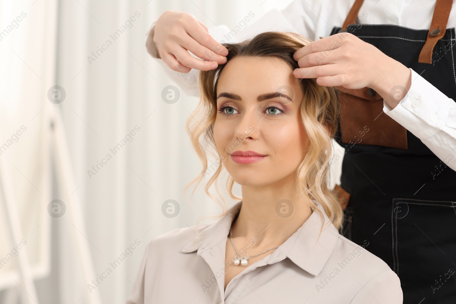 Photo of Hair styling. Professional hairdresser working with client in salon, closeup. Space for text