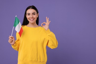 Photo of Happy young woman with flag of Italy showing OK gesture on violet background, space for text