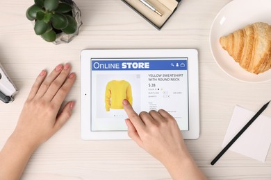 Photo of Woman with tablet shopping online at white wooden table, top view