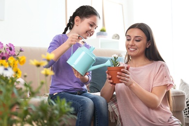 Mother and daughter watering potted plants at home