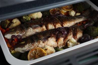 Baking tray with sea bass fish and vegetables, closeup