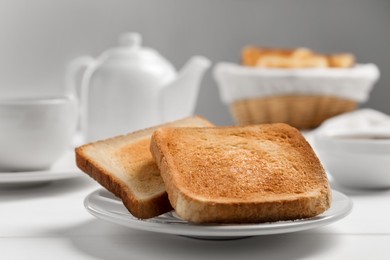 Slices of tasty toasted bread on white wooden table, closeup