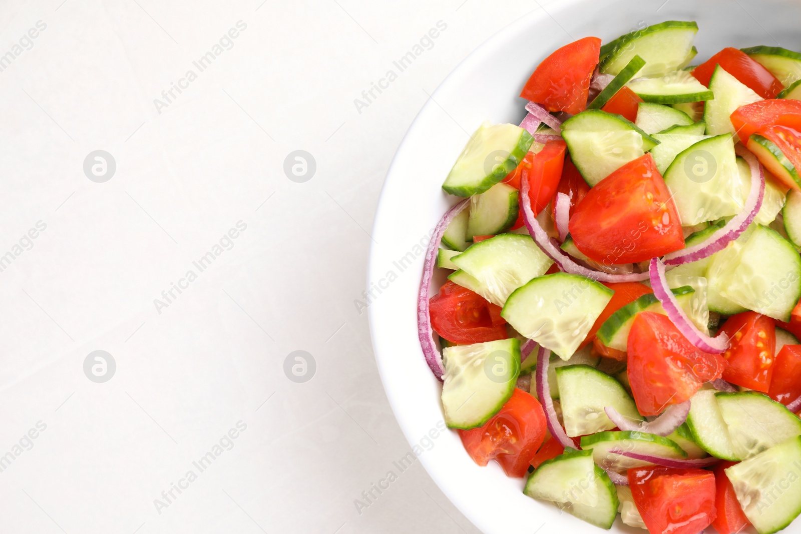 Photo of Delicious fresh cucumber tomato salad in bowl on table, top view. Space for text