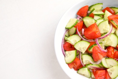 Photo of Delicious fresh cucumber tomato salad in bowl on table, top view. Space for text