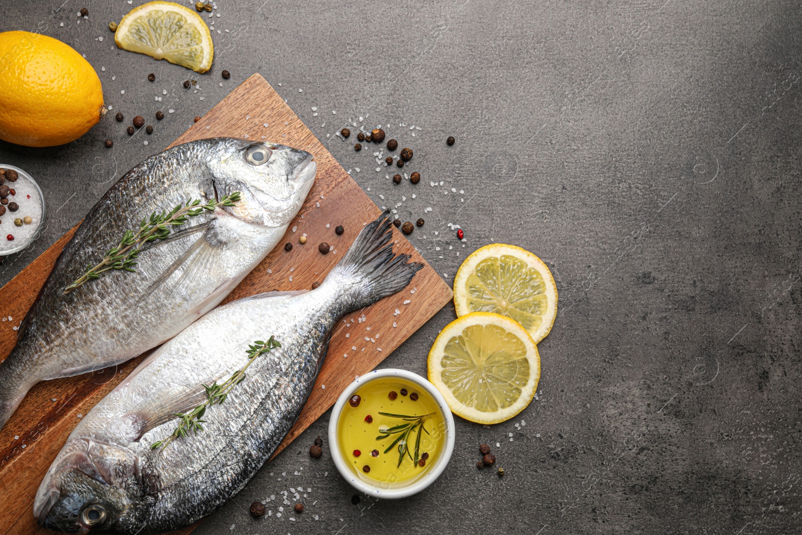 Photo of Fresh dorado fish and ingredients on black table, flat lay. Space for text