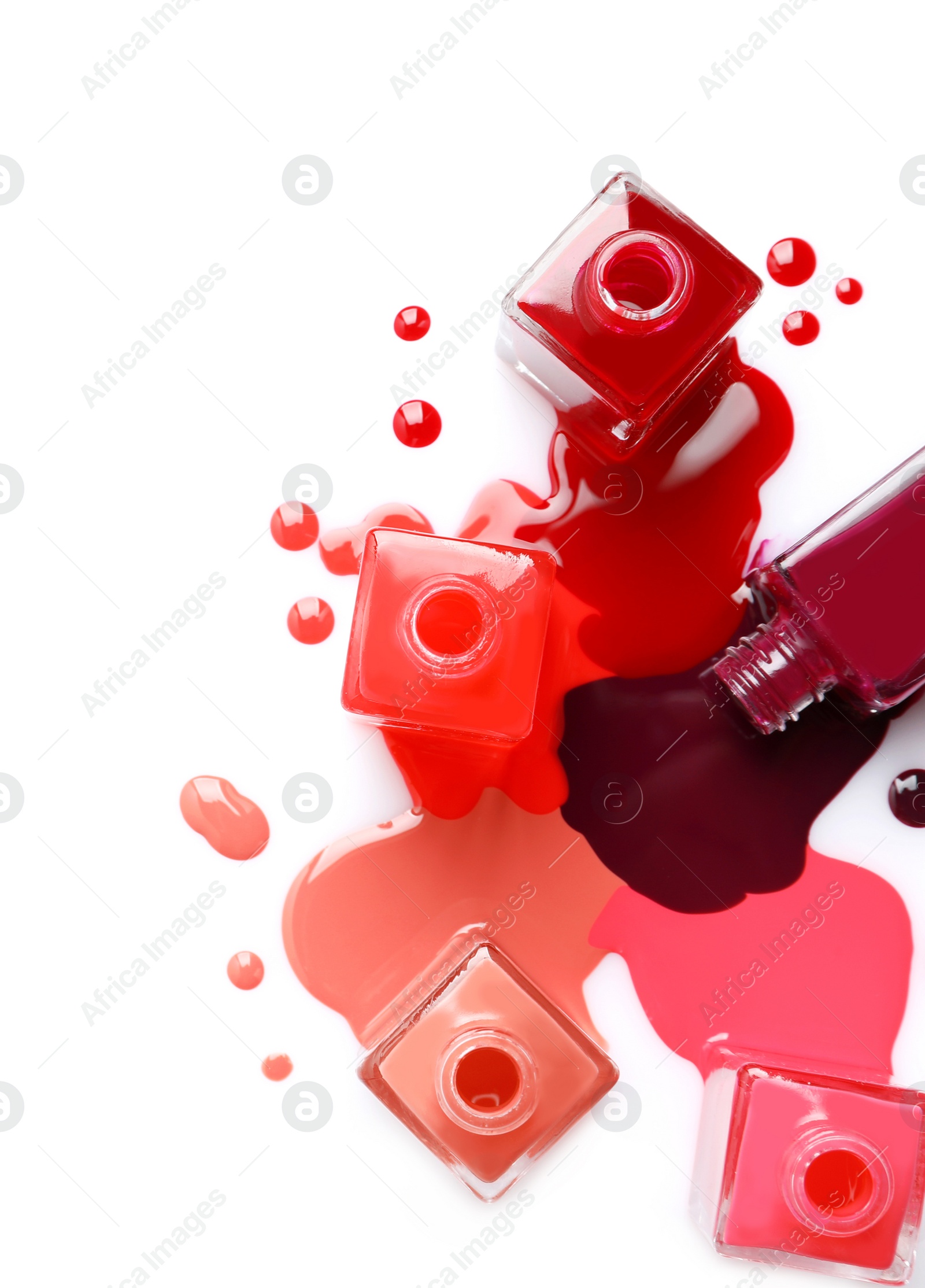 Photo of Spilled different nail polishes with bottles on white background, top view