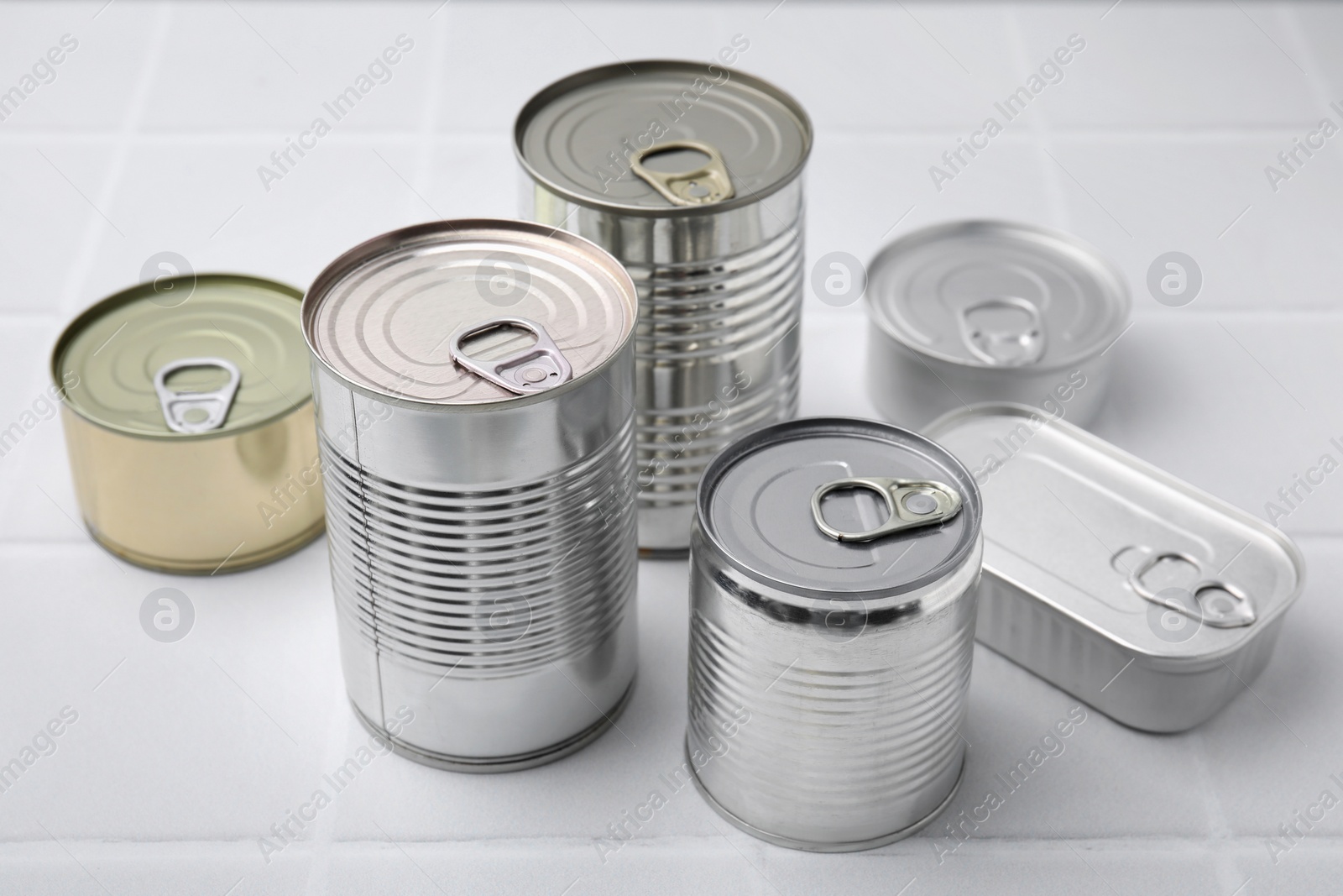 Photo of Many closed tin cans on white tiled table