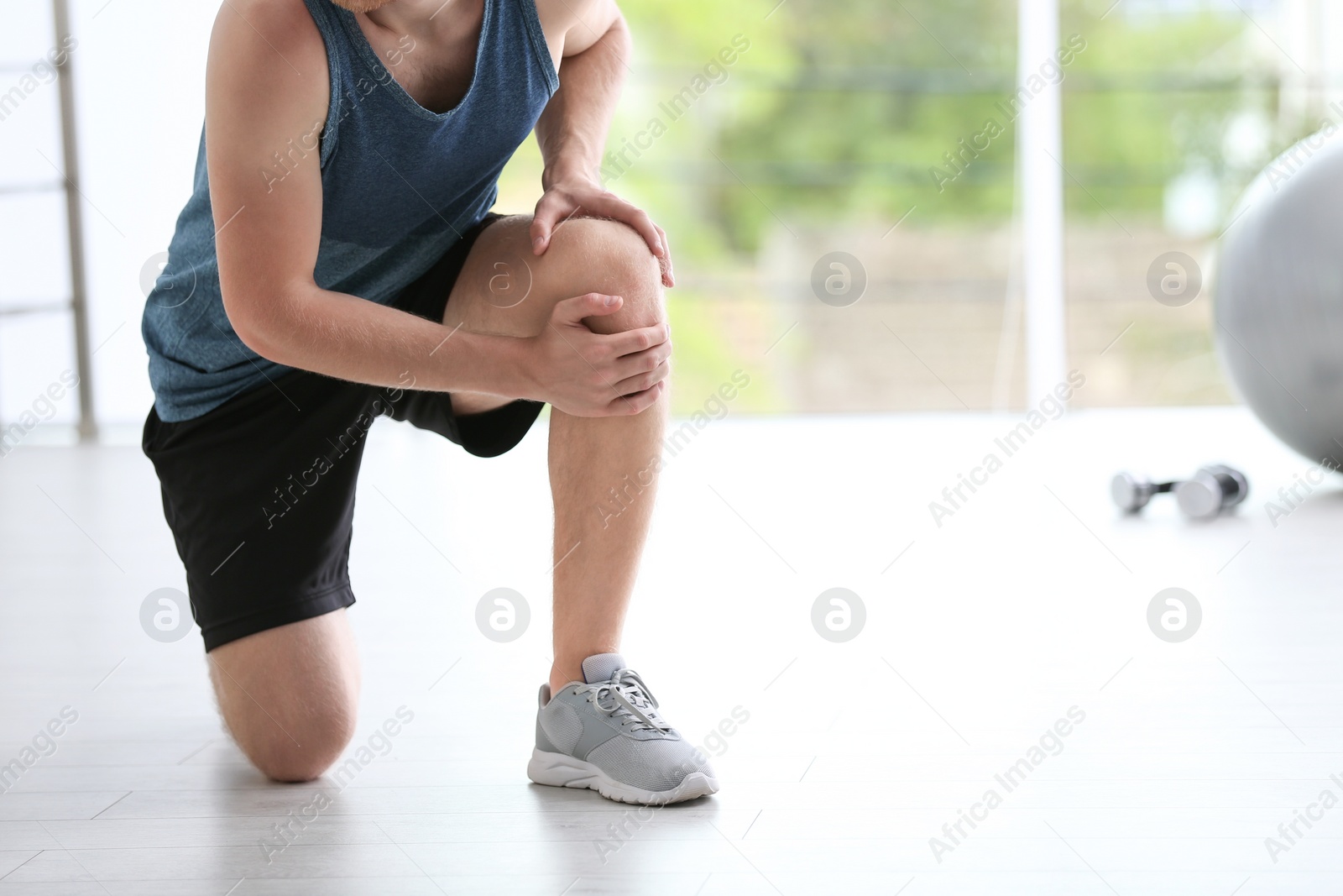 Photo of Man in sportswear suffering from knee pain at gym, closeup