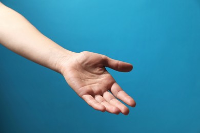 Woman holding something in hand on light blue background, closeup