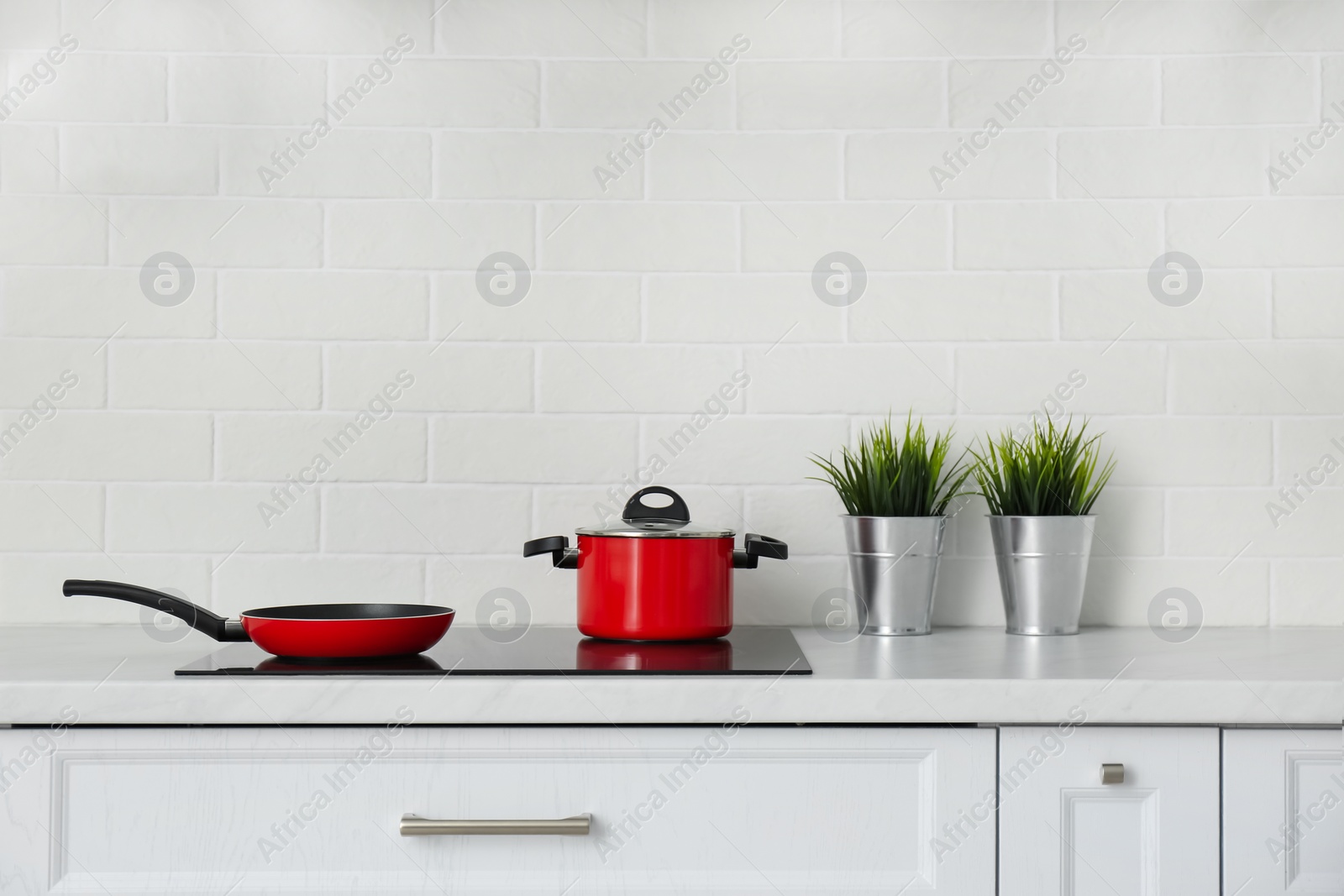 Photo of Saucepot and frying pan on induction stove in kitchen