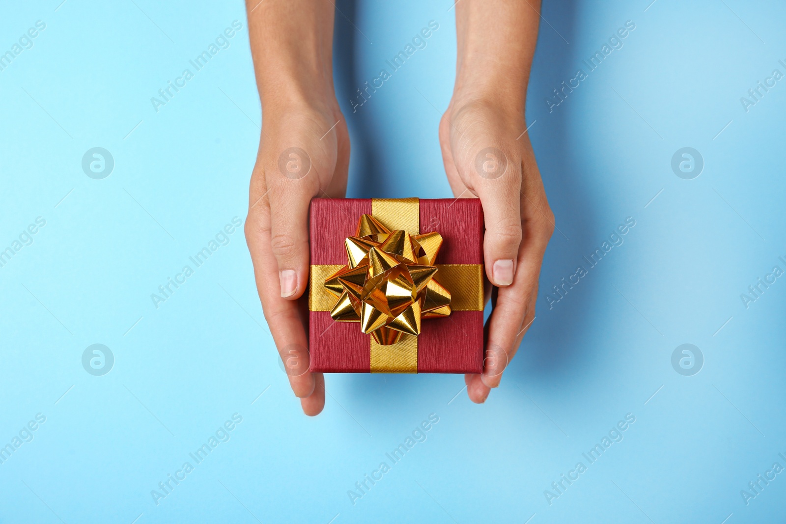 Photo of Woman holding beautiful gift box on blue background, top view