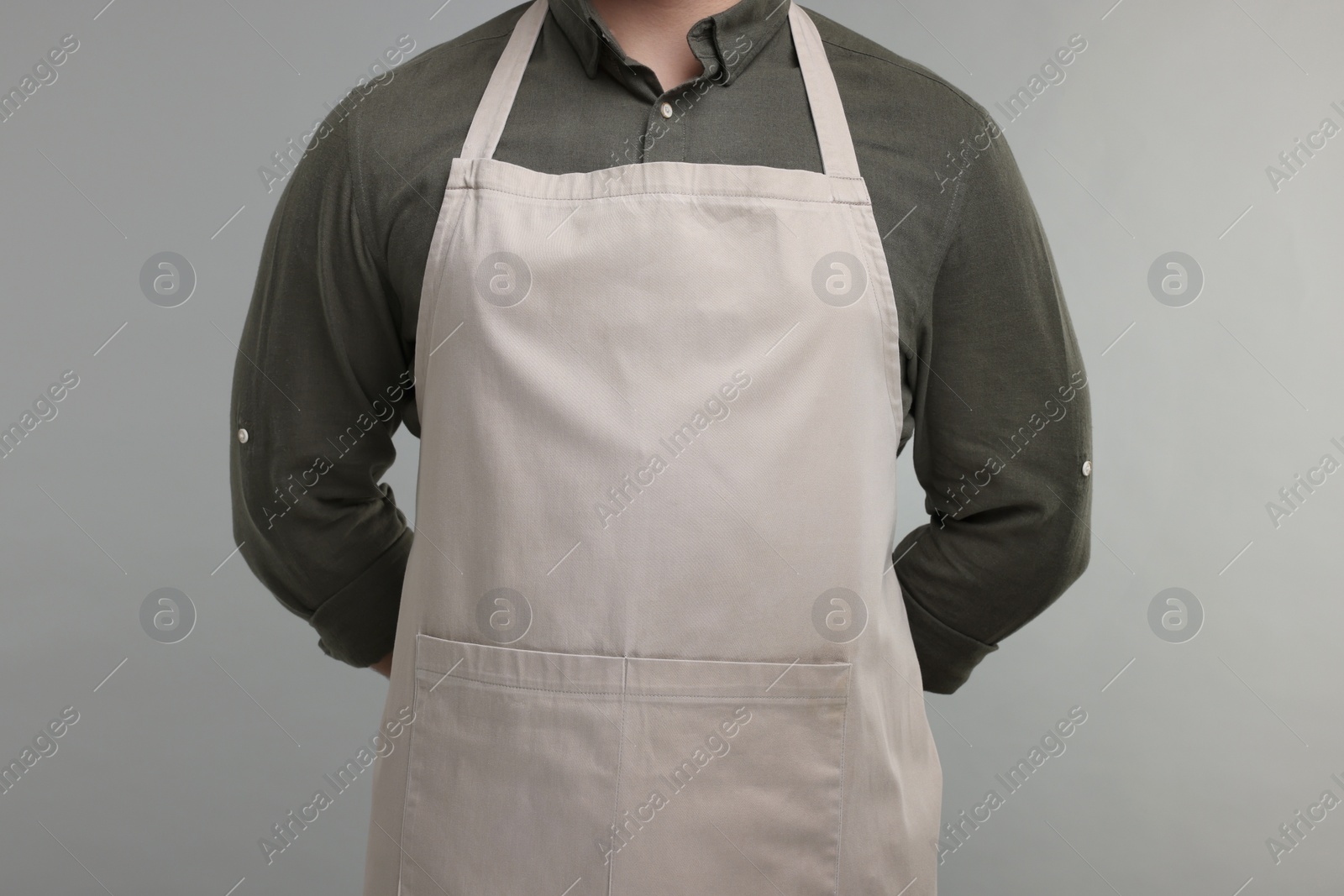 Photo of Man in kitchen apron on grey background, closeup. Mockup for design