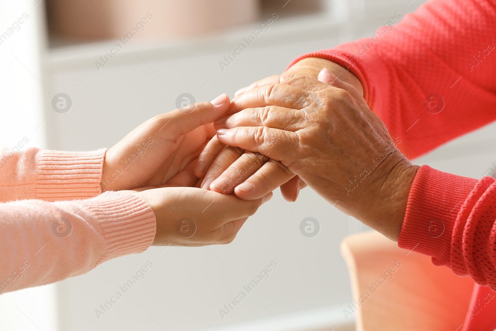 Photo of Helping hands on blurred background, closeup. Elderly care concept