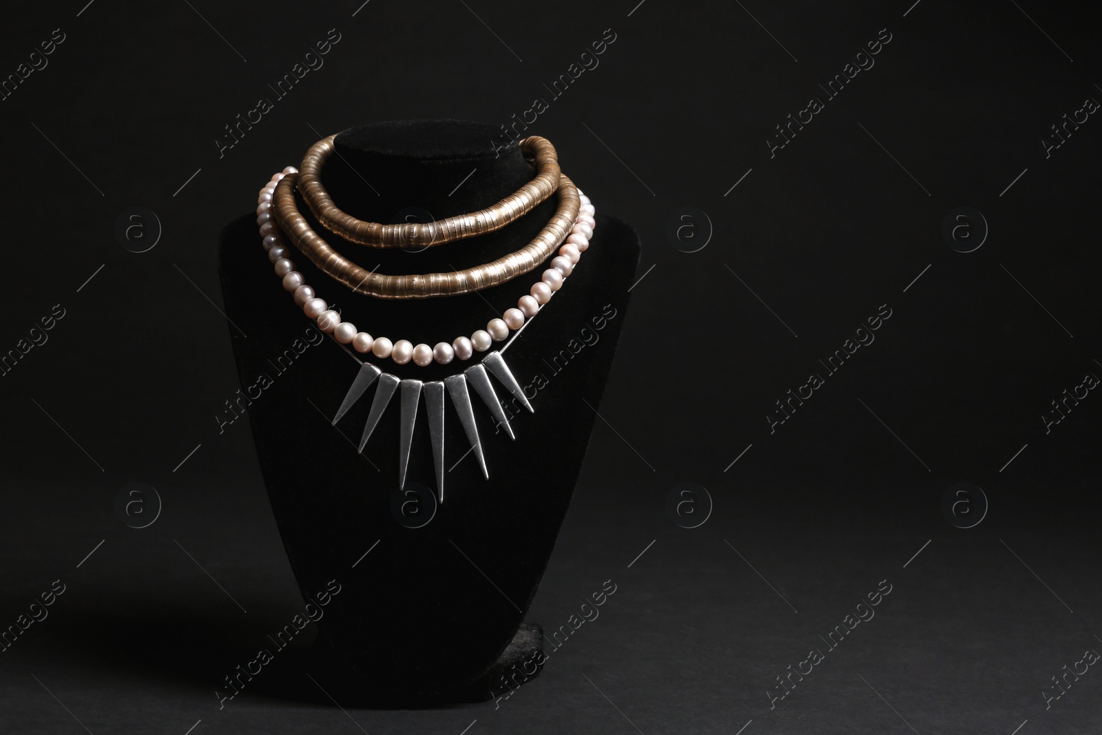 Photo of Stylish necklaces on stand against black background, space for text. Luxury jewelry