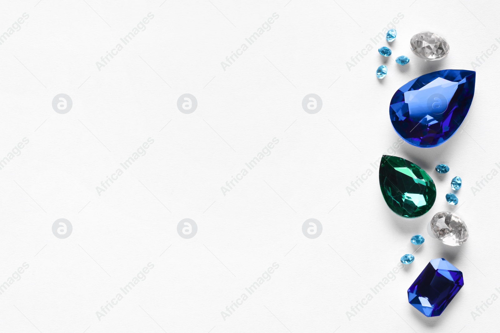 Photo of Different beautiful gemstones for jewelry on white background, top view. Space for text