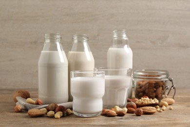 Photo of Different nut milks in glassware on wooden table