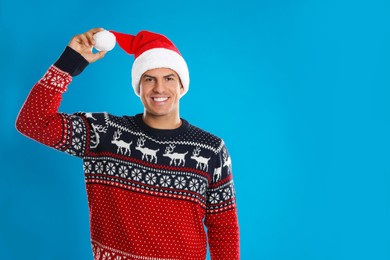 Photo of Happy man in Santa hat on blue background, space for text. Christmas countdown