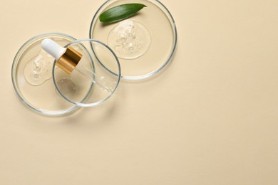 Photo of Petri dishes with samples of cosmetic oil, pipette and green leaf on beige background, flat lay. Space for text