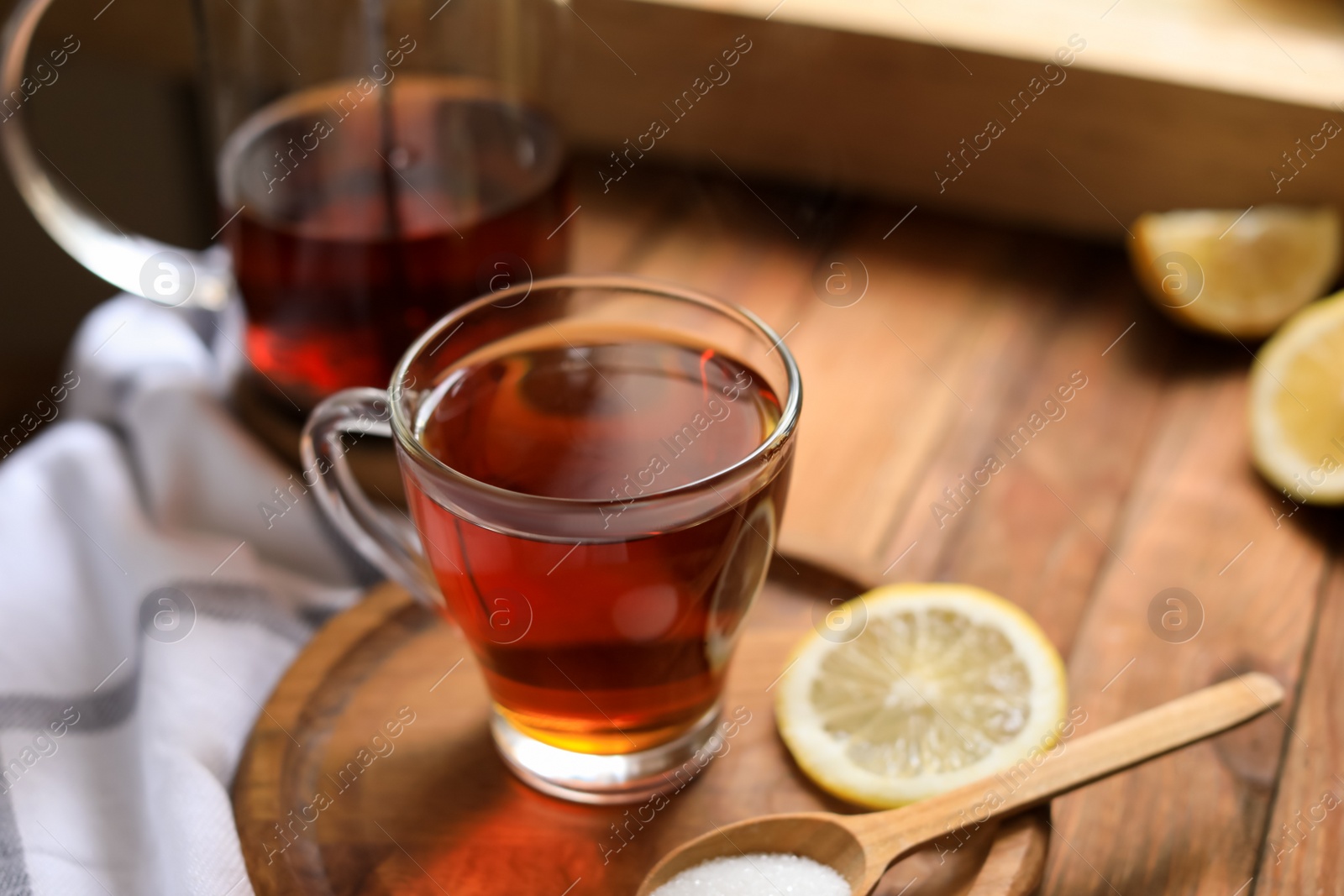 Photo of Glass cup with delicious tea, lemon and sugar on table, closeup. Space for text