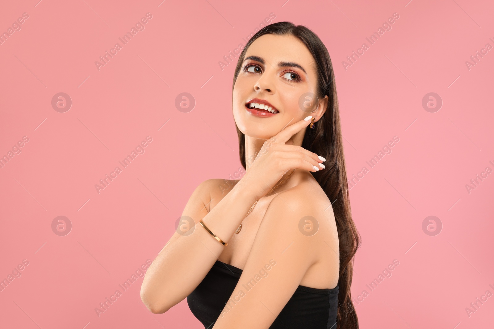 Photo of Beautiful woman with elegant jewelry on pink background, space for text